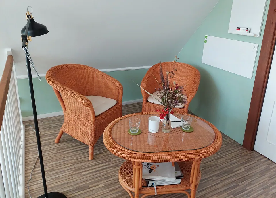 Two wicker chairs and a round table in the attic studio.