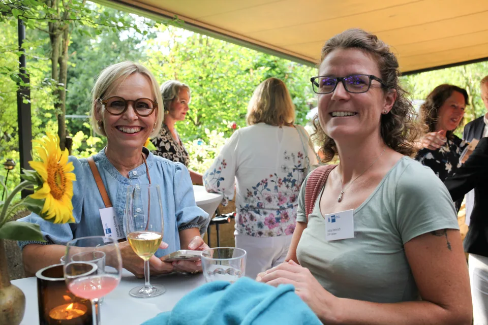 Two smiling event guests at a table on the covered terrace.