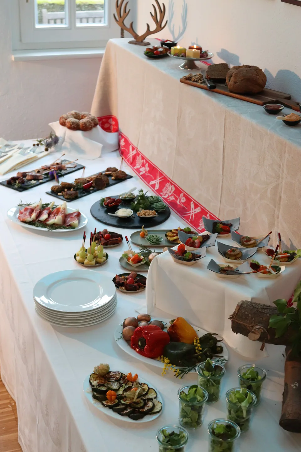 A buffet with small portions on tiered stands, bread and cutlery.