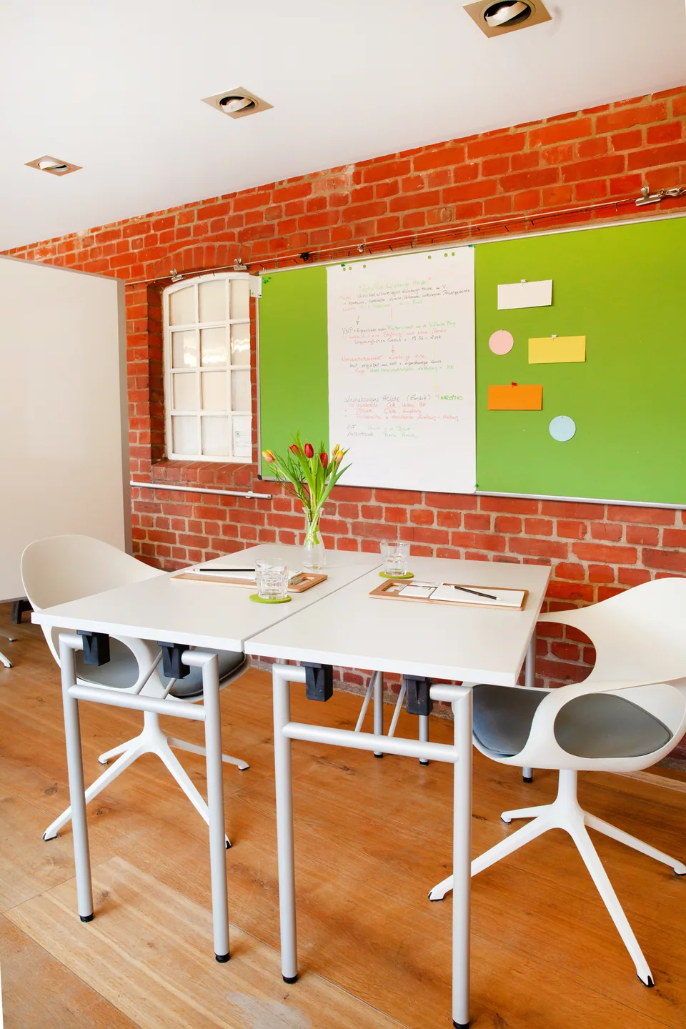 Prepared tables with clipboards and pens in front of a green pinboard in the Main Meeting Room.