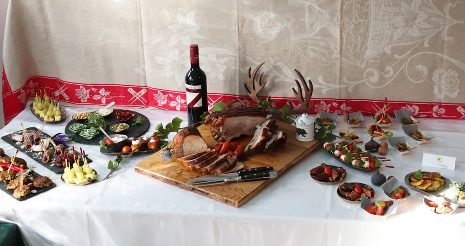 Buffet mit aufgeschnittenem Braten auf einem Holzbrett und kleinen herzhaften Speisen ringsherum.